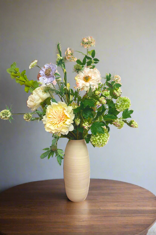 Vase with flowers on a pink surface and white background